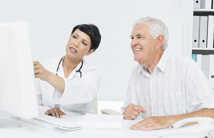 (c) wavebreakmedia/Shutterstock.com Ärztin betreut älteren Patienten vor einem Bildschirm